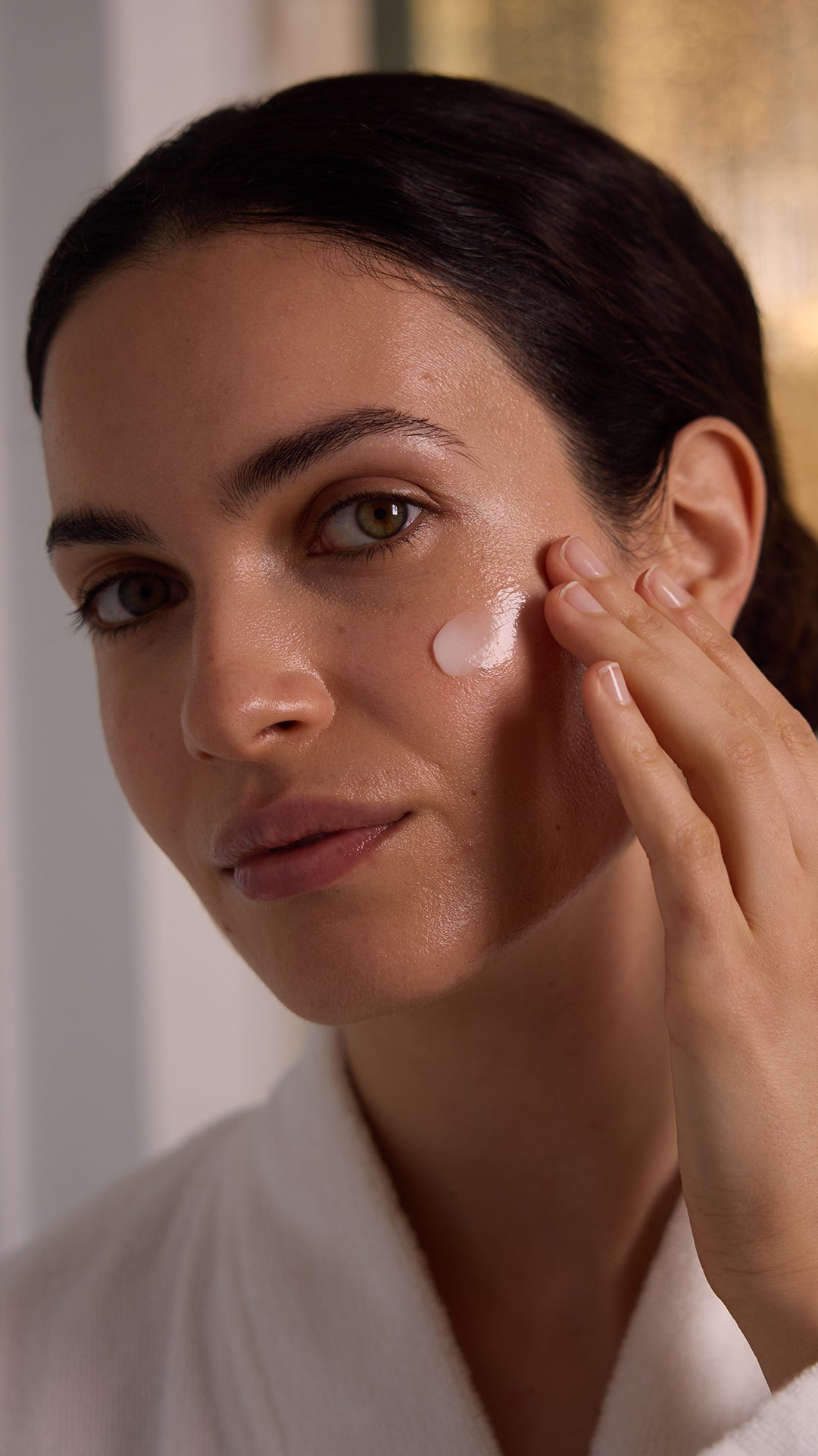 Image of model apply moisturizer to her cheek body with fingers