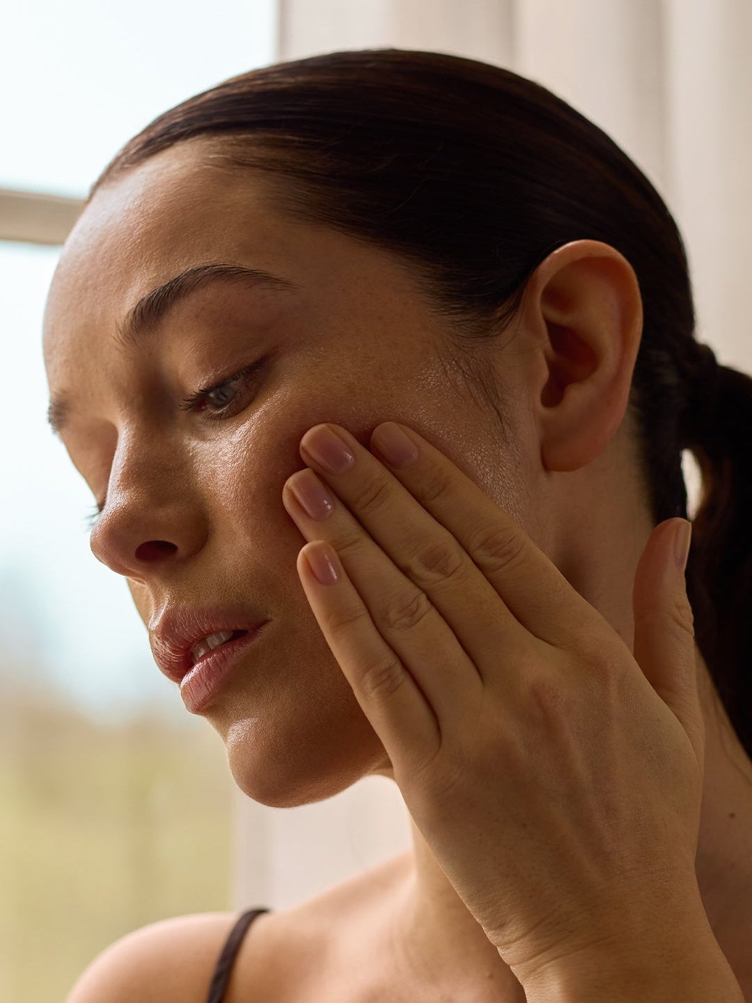 Model applying Optimal Pro Serum on cheek