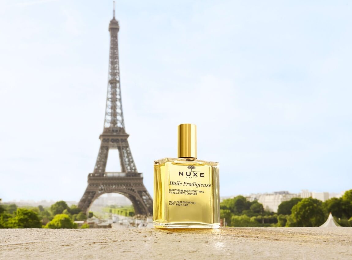 Golden Huile Prodigieuse Bottle in front of the Eiffel Tower