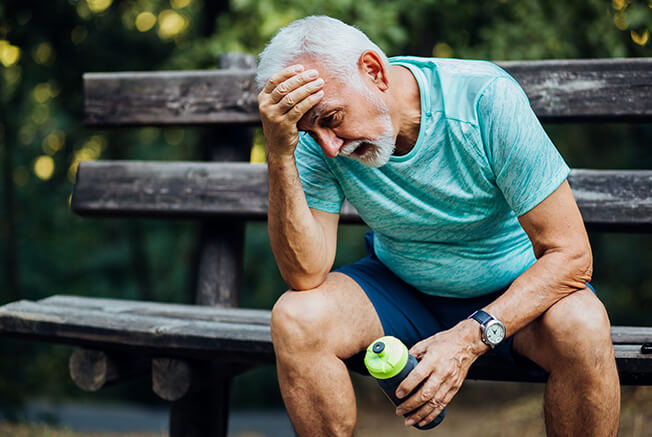 Man looking tired sat on a bench